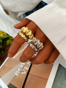 Primer plano de anillos apilados de oro y plata usados con jeans azules y camisa blanca
