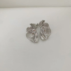 Macro shot of silver petal earrings featuring textured metal and teardrop zircon stones