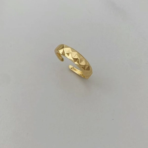 Macro de un anillo dorado ajustable con textura geométrica de rombos tallados