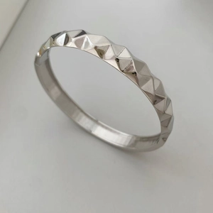 Detalle de brazalete plateado con textura geométrica y superficie facetada pulida