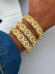 Close-up of three vintage gold brushed bangles with hollow floral diamond motifs