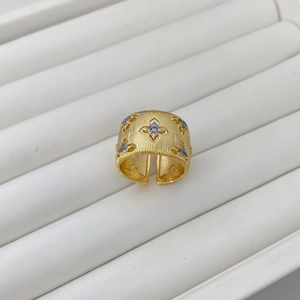 Detail of gold wide cuff ring with brushed texture, hollow flowers, and diamond accents