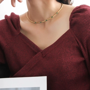 Détail du collier en or 18 carats avec zircons vert émeraude porté par le modèle