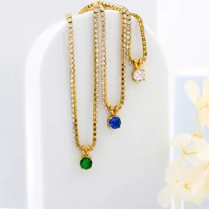 Gold tennis chain birthstone necklaces with large round gemstone pendants on white stands