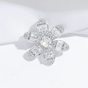 Elegant floral brooch with sparkling crystals and a central gemstone on white silk background