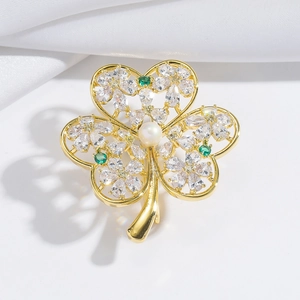 Broche trèfle élégante en or avec zircons brillants et perle blanche sur fond de soie blanche