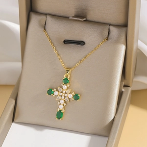 Elegant gold cross necklace with green stones and pearls displayed in a luxury gift box