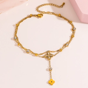 Detail einer goldenen zweischichtigen Fußkette mit Kleeblatt-Kristall und Blumenquasten