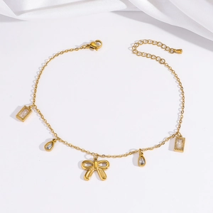 Makroansicht der goldenen Fußkette mit Schmetterling und Kristallanhängern auf Seide