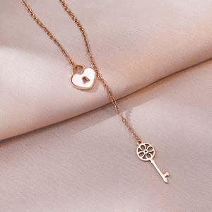 Rose gold heart lock and key pendant necklace displayed on soft pink fabric texture