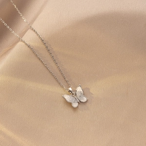 Vista detallada del collar de mariposa sobre seda champán con alas de efecto irisado