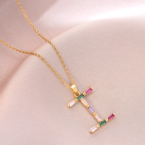 Détail du pendentif lettre I doré avec zircons colorés sur un tissu de soie doux
