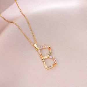 Détail du collier pendentif lettre B doré avec zircons colorés sur soie rose