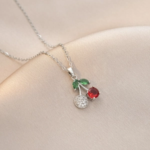 Détail macro d'un pendentif cerise avec pierres précieuses sur fond de soie douce