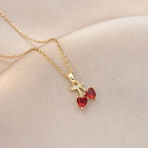 Détail macro du pendentif cerise avec cristaux cœur rouges et feuille dorée diamantée