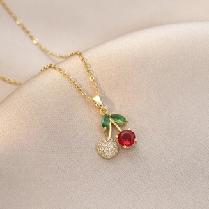 Détail d'un collier avec pendentif cerise doré orné de gemmes rouges et vertes