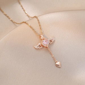 Rose gold heart necklace with angel wings and pink stone on a champagne silk background