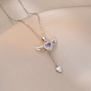 Detail of angel wing heart pendant with purple zircon on champagne silk background