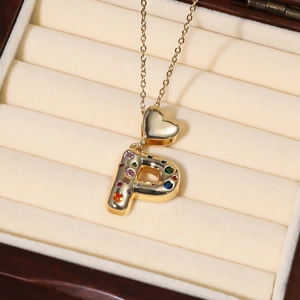 Goldkette mit poliertem Herz und buntem Zirkonia P-Buchstabenanhänger auf weißem Futter