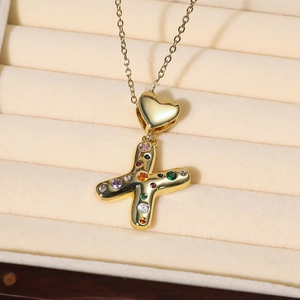 Makroaufnahme der Goldkette mit Herzverschluss und X-Anhänger mit bunten Zirkoniasteinen