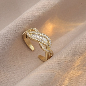 Bague ouverte nœud en zircons dorée 18 carats sur un fond élégant en soie brillante