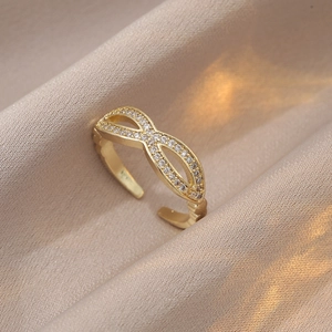 Vue détaillée d'une bague symbole infini avec zircons blancs sur satin de couleur champagne