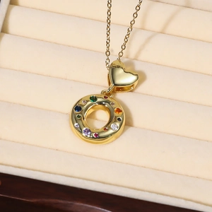 Detail einer goldenen Halskette mit herzförmigem Bügel und buntem Edelstein-Ringanhänger