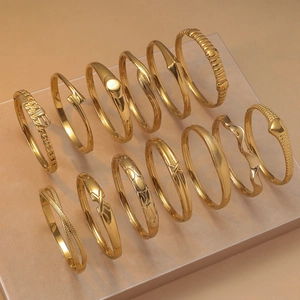 Collection of golden titanium steel bangles with minimalist and embossed textures