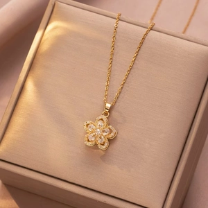 Elegant gold flower rotating pendant necklace with clear zircon stones on a jewelry box