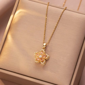 Rotating pink flower necklace in gold finish with zircon petals on jewelry box