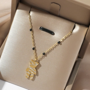 Detailed shot of golden bear pendant with white zircons and black beads on a gold necklace