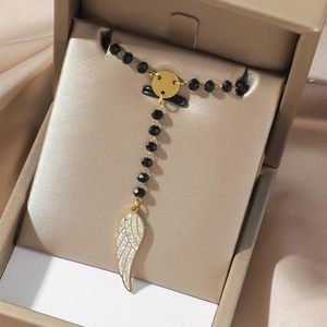 Close-up of golden angel wing pendant with black beads and sparkling crystals details