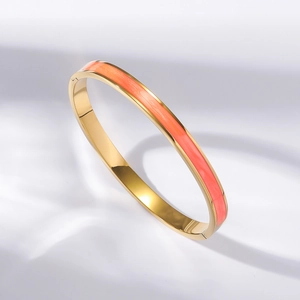 Detailed macro shot of a gold-plated stainless steel bracelet with orange enamel finish