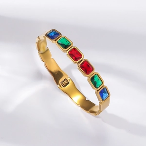 Detail view of gold titanium steel bangle with colorful rectangular emerald cut gemstones