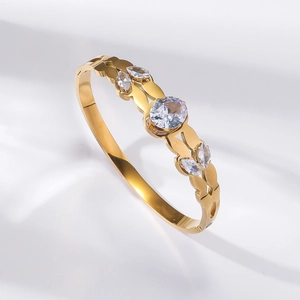 Detail of gold titanium steel bangle showing wavy cutout design and sparkling cubic zirconia