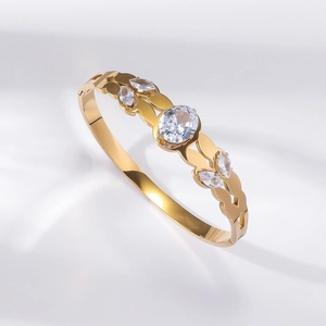 Detail of gold-plated bangle with wave design and five sparkling transparent gemstones
