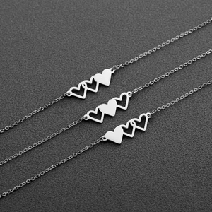 Gros plan de trois colliers en forme de cœur argenté avec pendentifs en acier poli