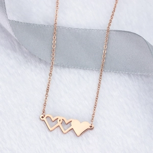 Détail du collier à trois cœurs superposés or rose sur fond en peluche douce blanche