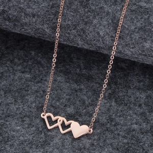 Gros plan d'un pendentif triple cœur en or rose avec des breloques évidées et polies