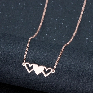 Détail macro d'un pendentif à trois cœurs en or rose sur fond noir texturé élégant