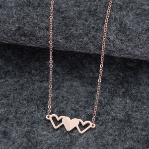 Détail du pendentif triple cœur en or rose avec des formes de cœur polies et ajourées sur feutre