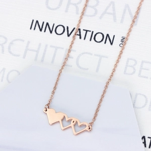 Gros plan d'un collier à trois cœurs imbriqués avec une finition en or rose poli