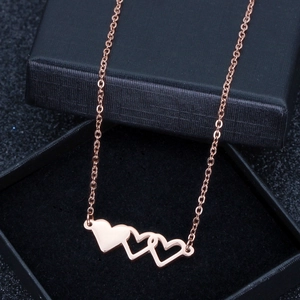 Détail de la chaîne avec pendentifs triple cœur en or rose sur boîte noire