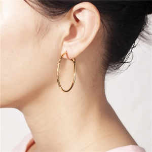 Dettaglio di orecchini a cerchio geometrici placcati oro con texture in metallo martellato