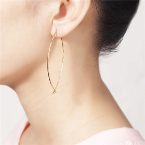Primo piano di orecchini a cerchio ovali geometrici placcati in oro su una modella
