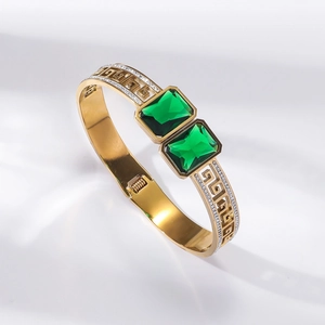 Elegant gold bangle with large green rectangular crystals and Greek key pattern