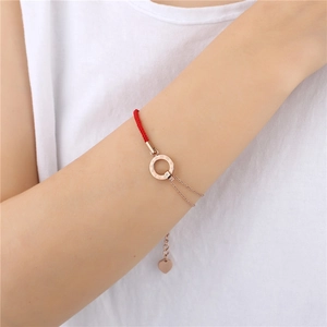 Detailansicht des roten Kordelarmbands mit roségoldenem römischem Ring und Herzanhänger