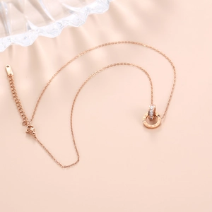 Macro shot of rose gold double interlocking rings necklace with Roman numerals and zircons