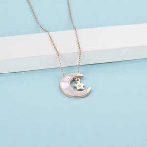 Macro shot of rose gold crescent moon pendant with mother-of-pearl and star charm