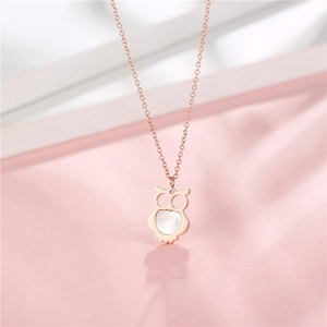 Rose gold owl necklace with white shell inlay and zircon stone on pink background